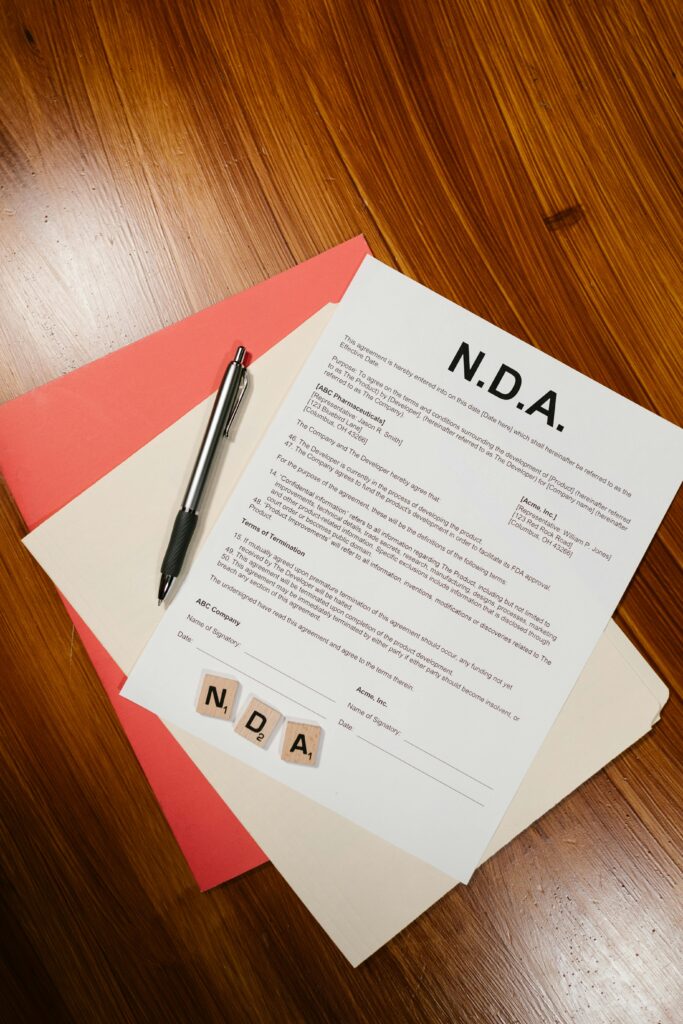 A close-up view of an NDA document, pen, and files on a wooden surface, perfect for legal or business themes.